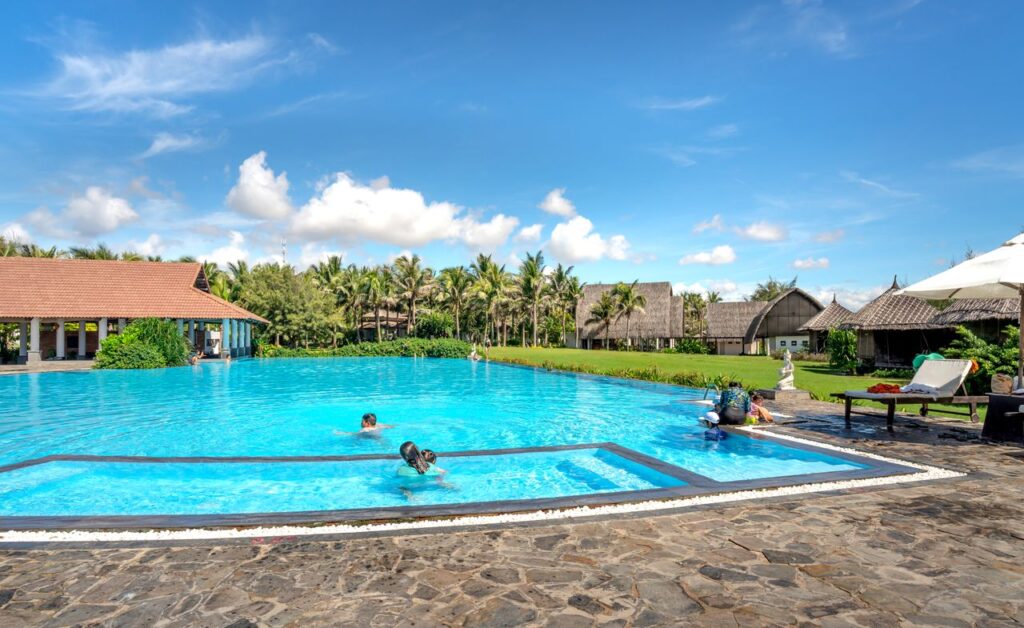 Luxurious tropical resort featuring a vibrant swimming pool under sunny skies, ideal for summer vacations.