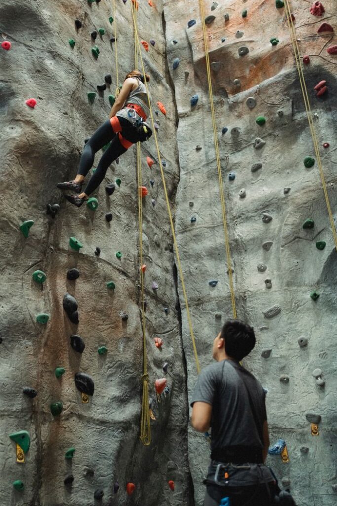 Concentrated unrecognizable alpinists in sportswear climbing on climbing wall during training in special gym